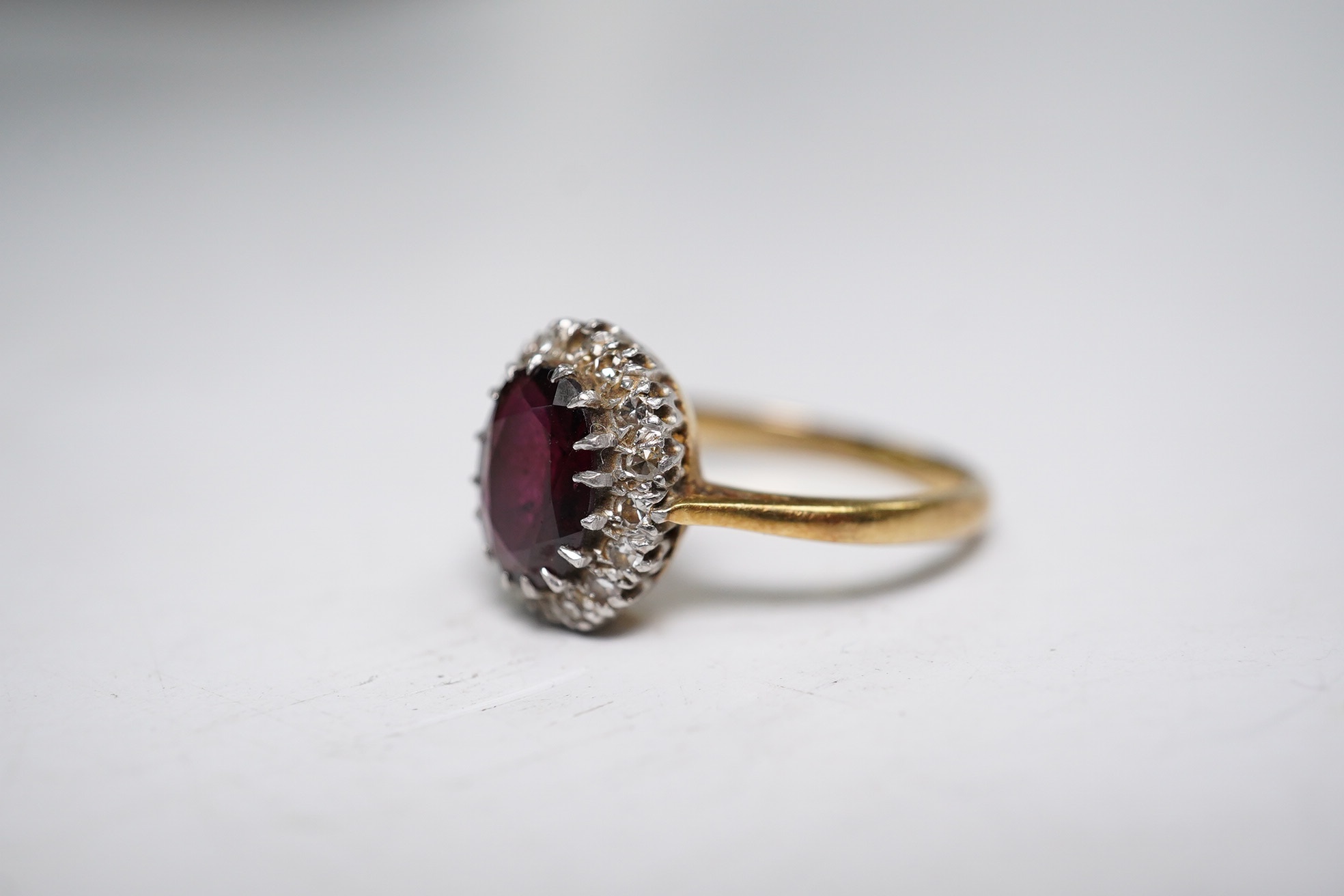 A 9ct and plat, garnet and diamond chip set oval cluster ring, size L, gross weight 3.9 grams. Condition - fair